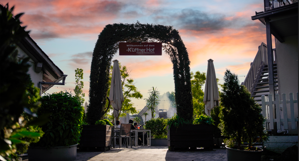Holzgebäude mit Lichterkette und immergrünem Zweig; Winterlandschaft.