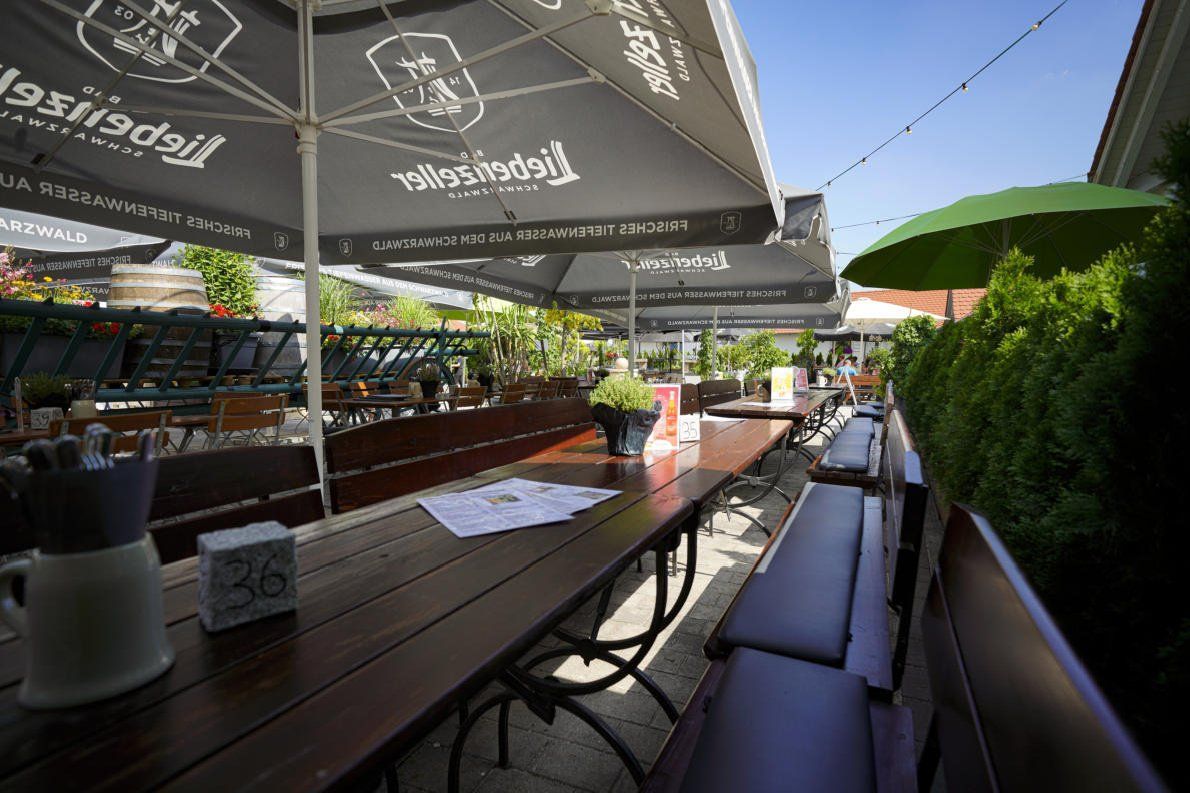 Zwei Krüge Bier stehen bei Sonnenuntergang auf einem Holztisch.