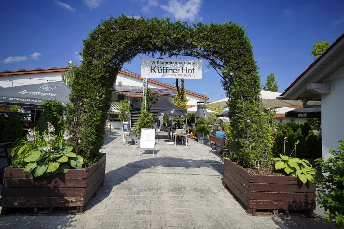 Ein langer Holztisch mit Tellern, Gläsern und Blumen darauf.