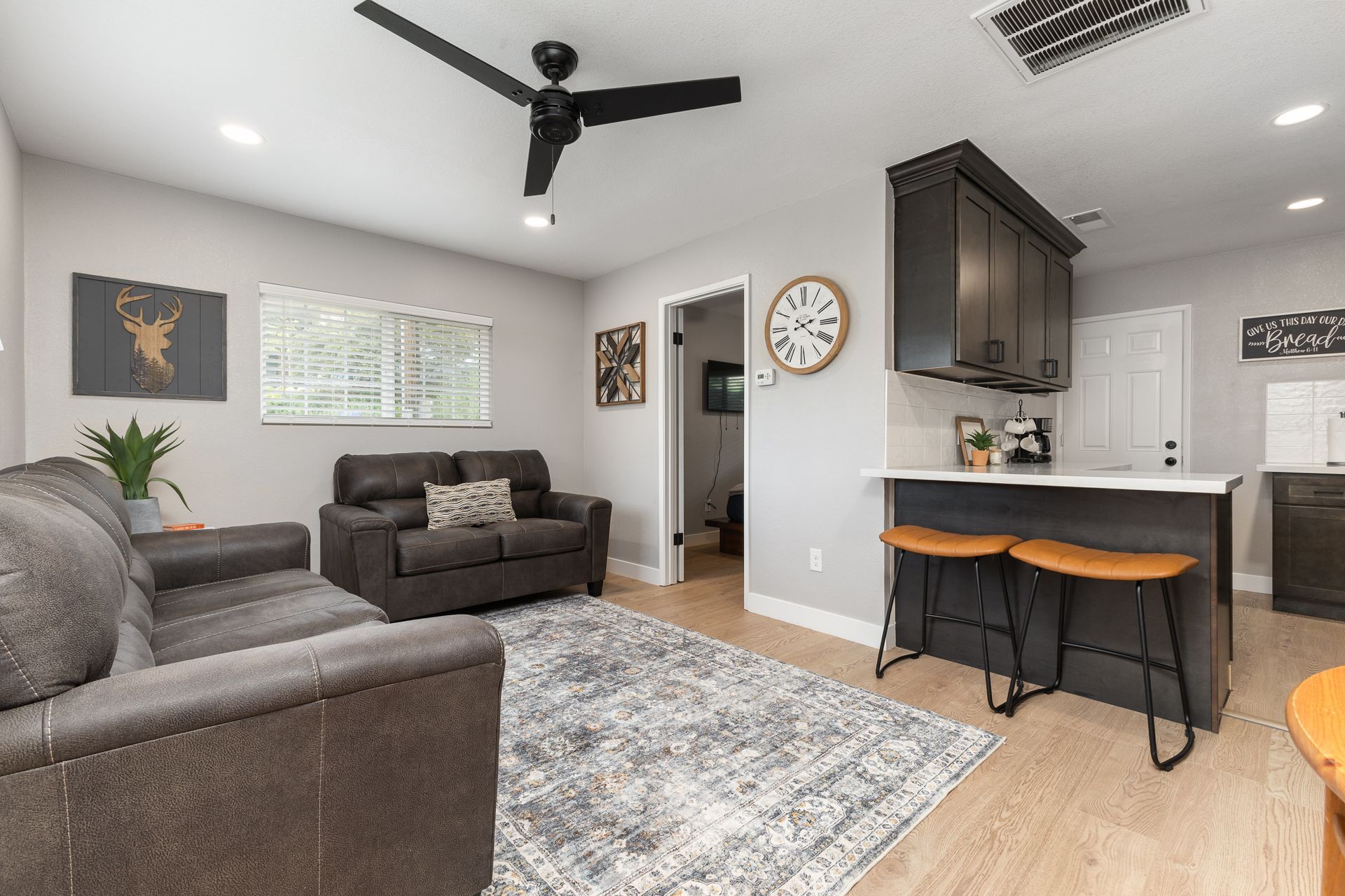Cozy living room with grey sofas, a kitchen bar, and a rug.