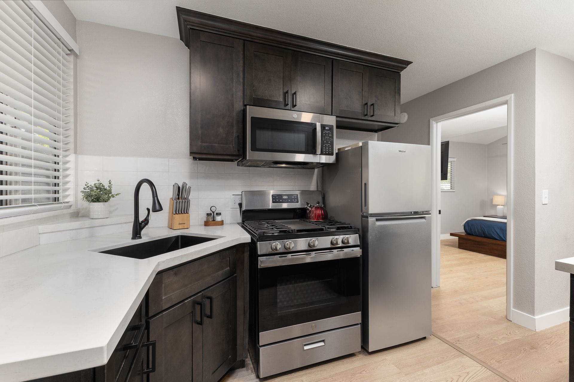 Small kitchen with dark cabinets, stainless steel appliances, and a white countertop.