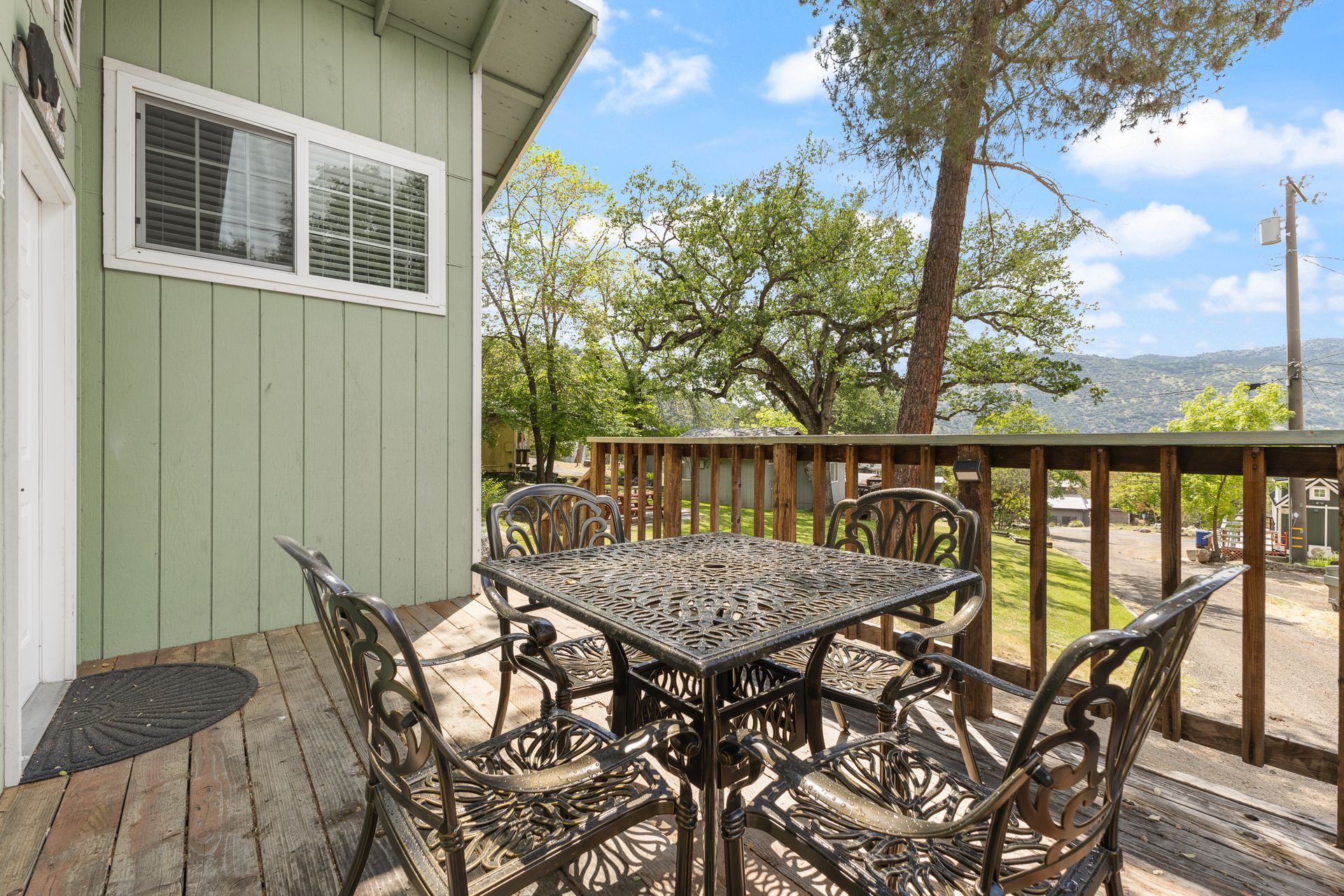 Patio with metal table and chairs, overlooking a hillside with trees.