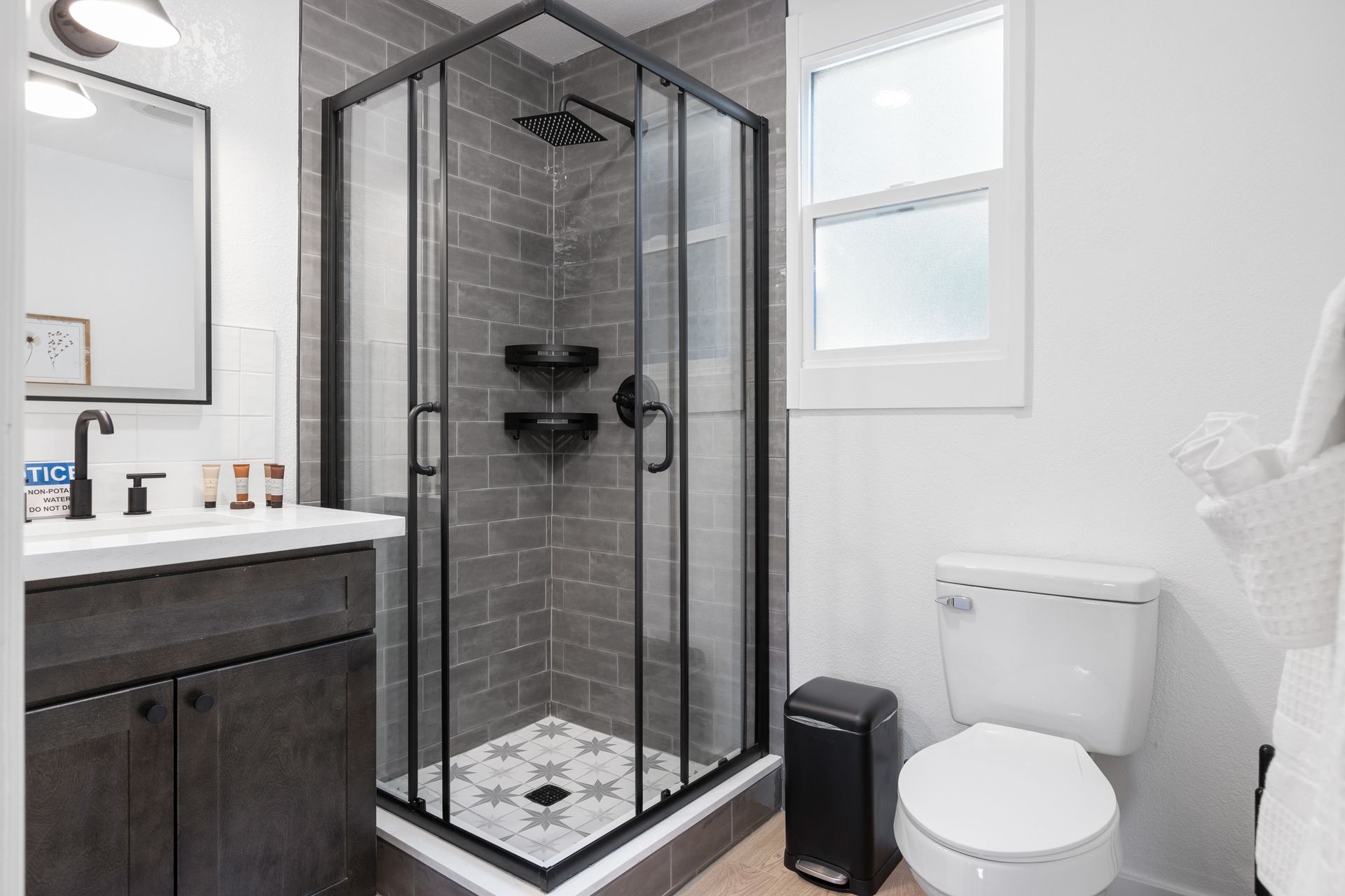 Bathroom with a shower, toilet, and vanity. Gray and white color scheme, modern design.