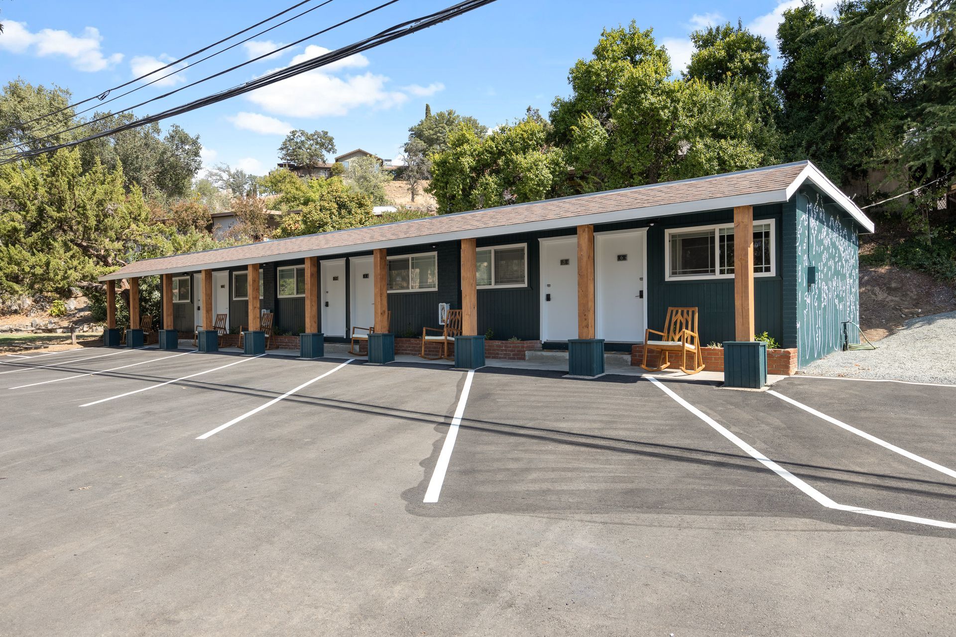 Motel with blue exterior, wooden posts, and asphalt parking lot.