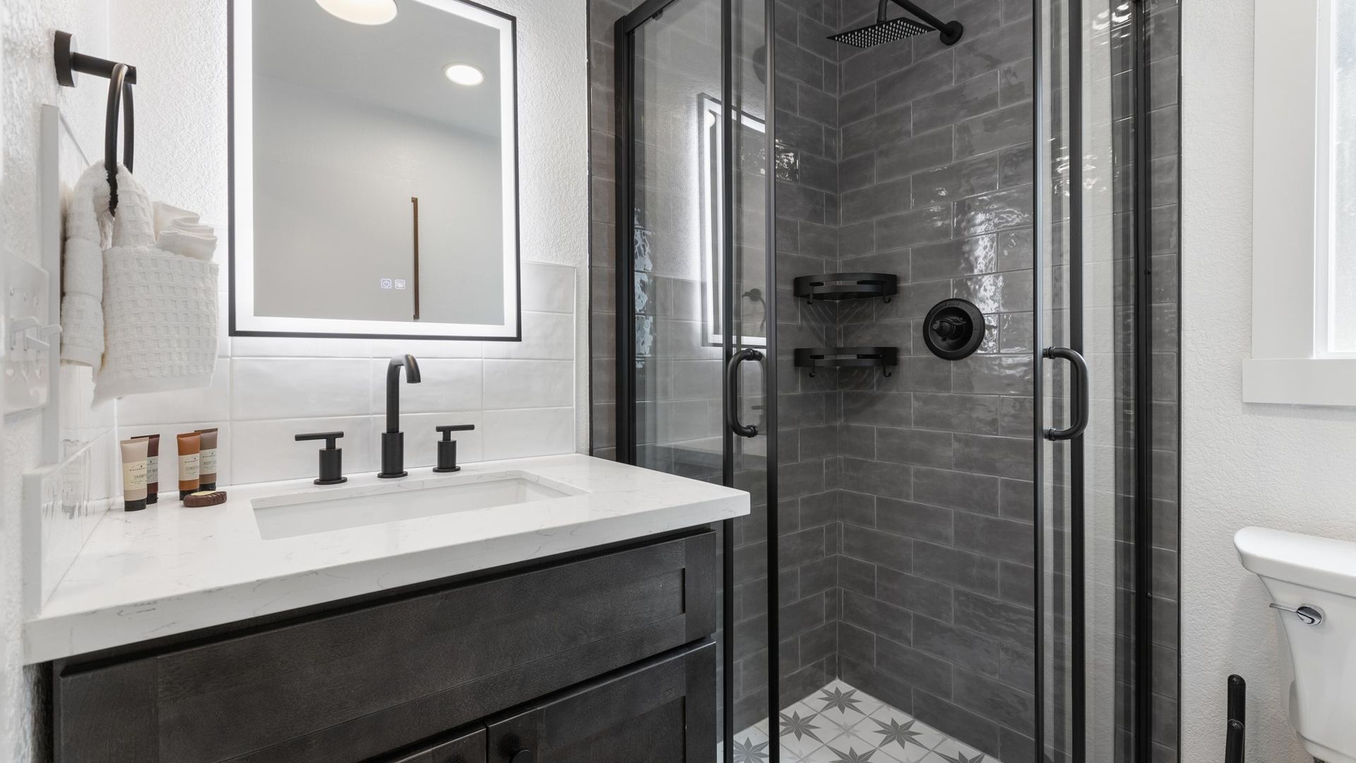 Modern bathroom with a gray vanity, glass shower, and white tile.