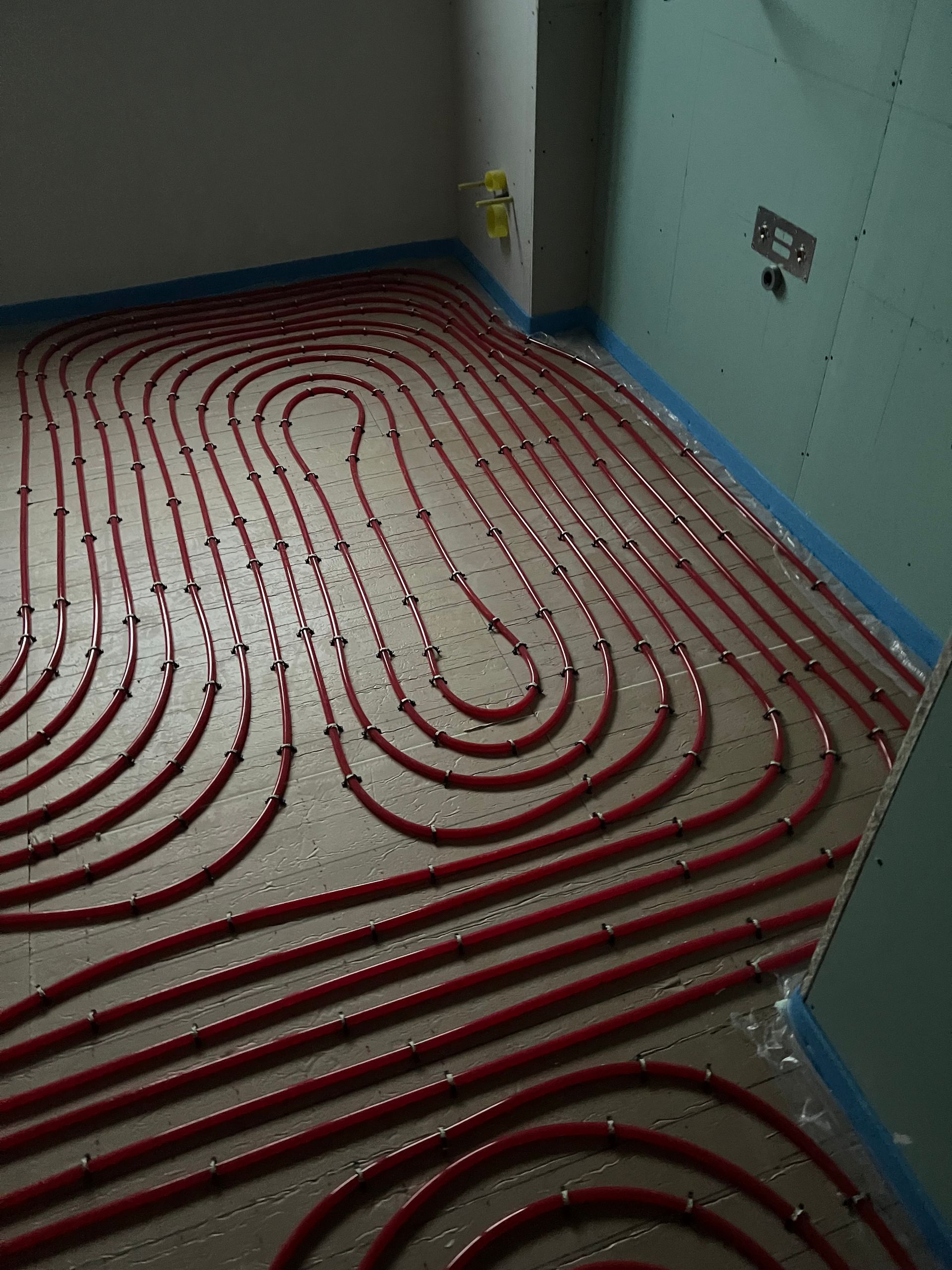 Tuyau rouge installé sur le sol d'une pièce, pour un chauffage au sol.