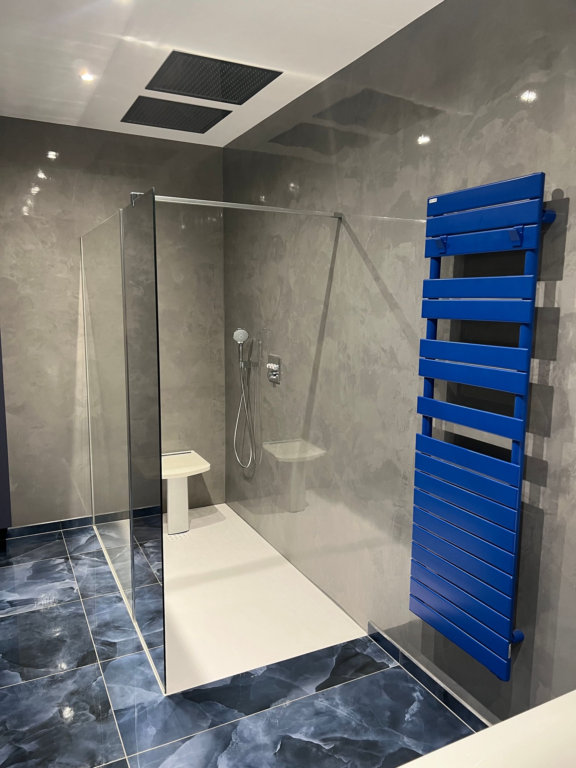 Toilettes blanches, mur carrelé gris et vases décoratifs sur une étagère.