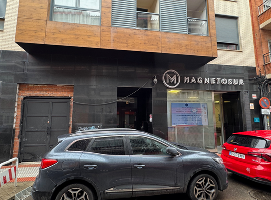 Un coche gris está aparcado delante de un edificio.