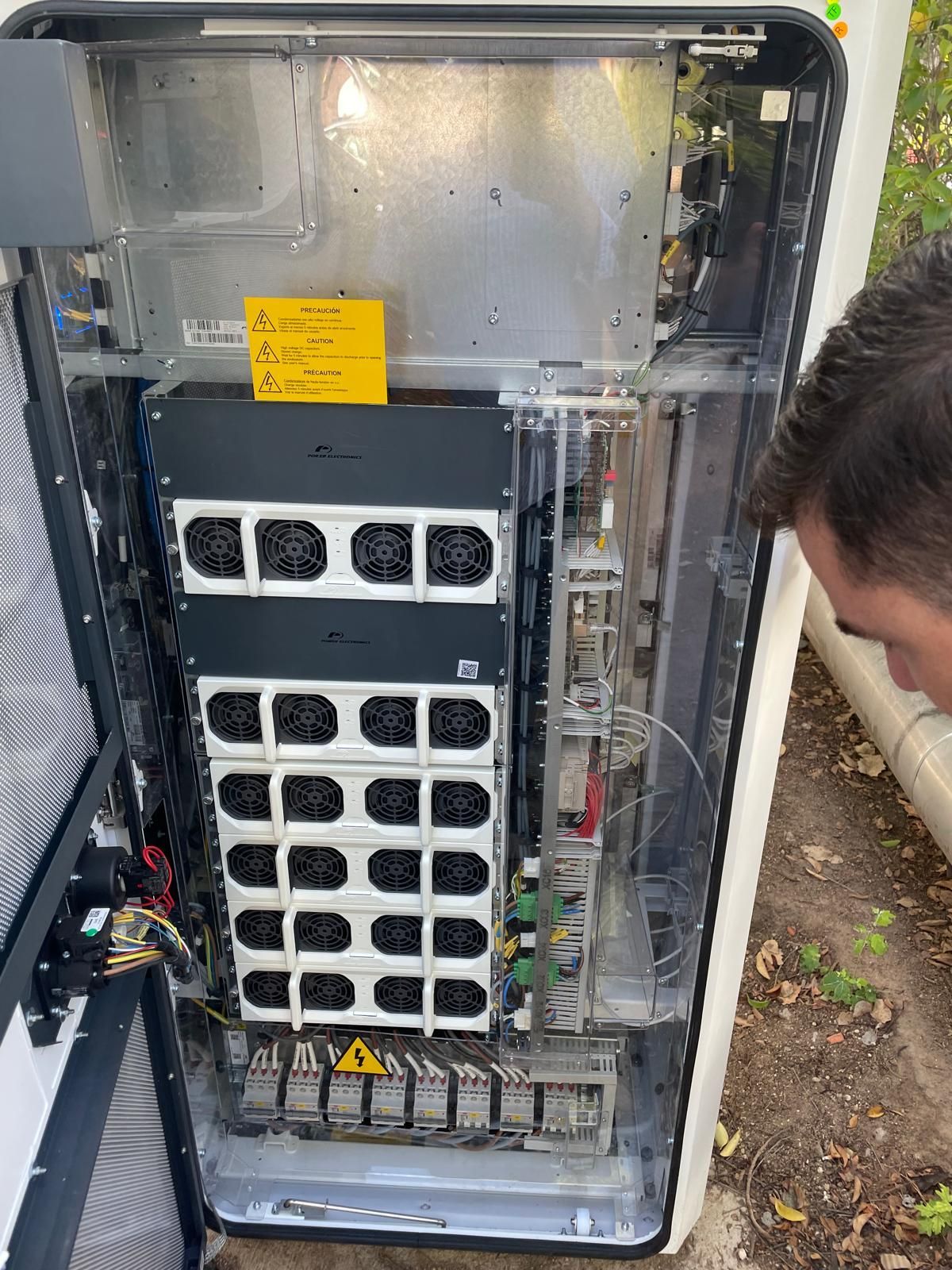 Un hombre está mirando el interior de una caja eléctrica.