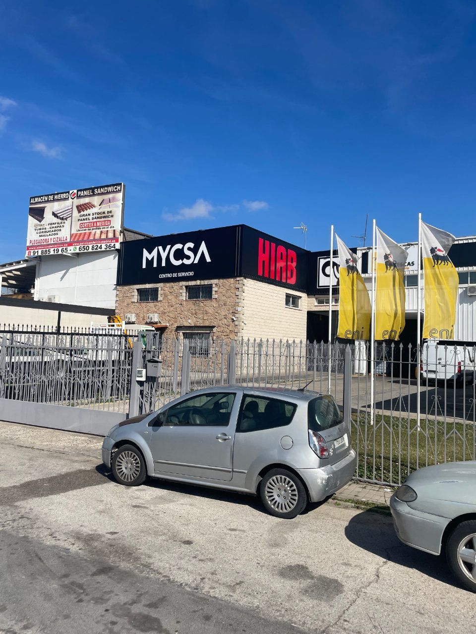 Un coche plateado está aparcado delante de un edificio que dice mycsa