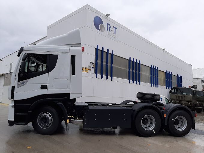 Un camión blanco está estacionado frente a un edificio que dice rt