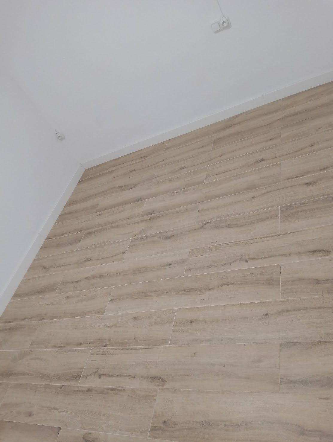 Una habitación con suelo de madera y paredes blancas.