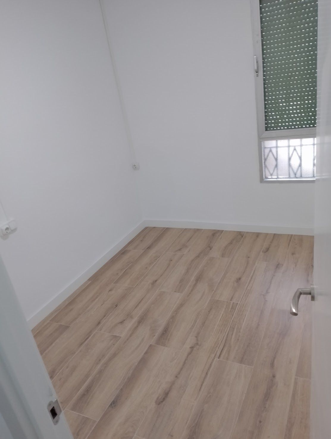 Una habitación vacía con suelo de madera y una ventana.