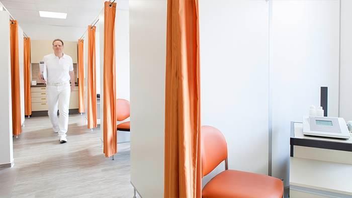 Ein Mann geht einen Flur in einem Krankenhaus entlang.