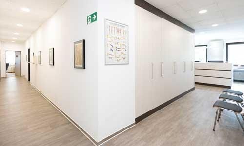 Ein langer Flur in einem Krankenhaus mit einem grünen Ausgangsschild an der Wand.