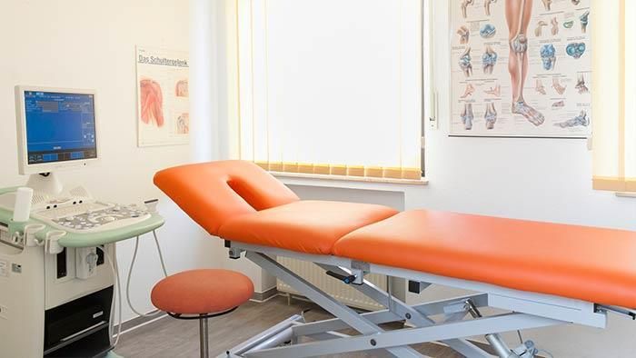 Eine Arztpraxis mit einem orangefarbenen Bett und einem Computer.