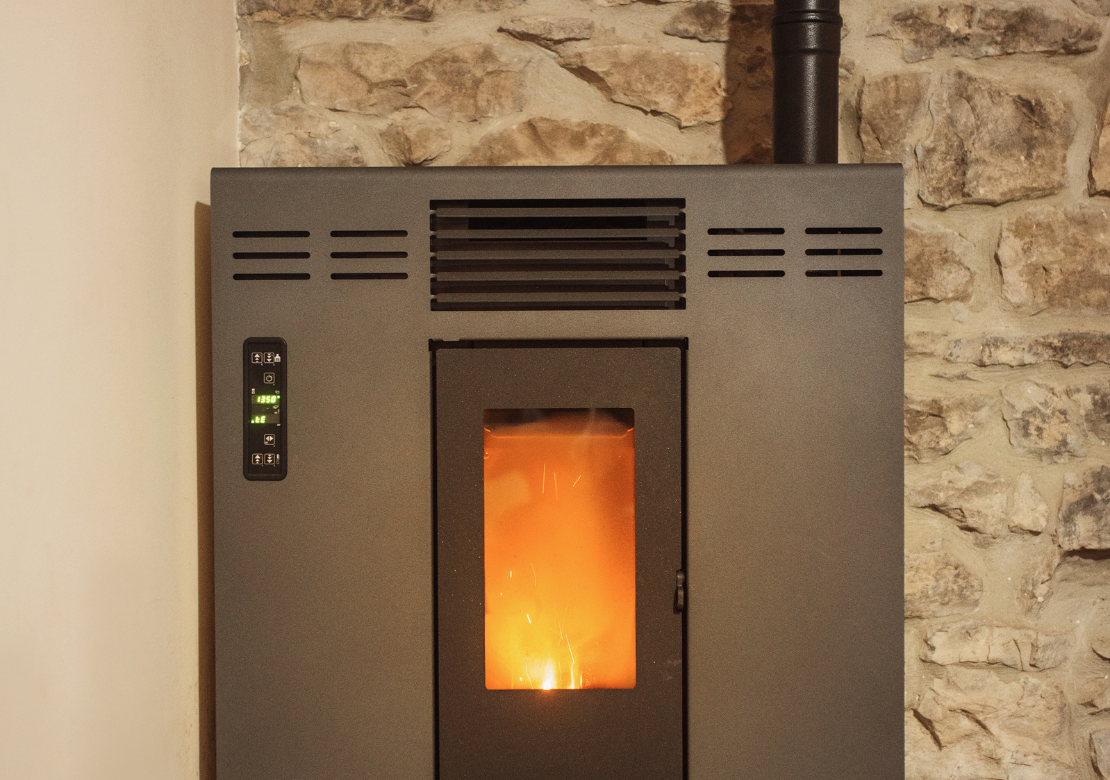 Un poêle à granulés est posé devant un mur en pierre.