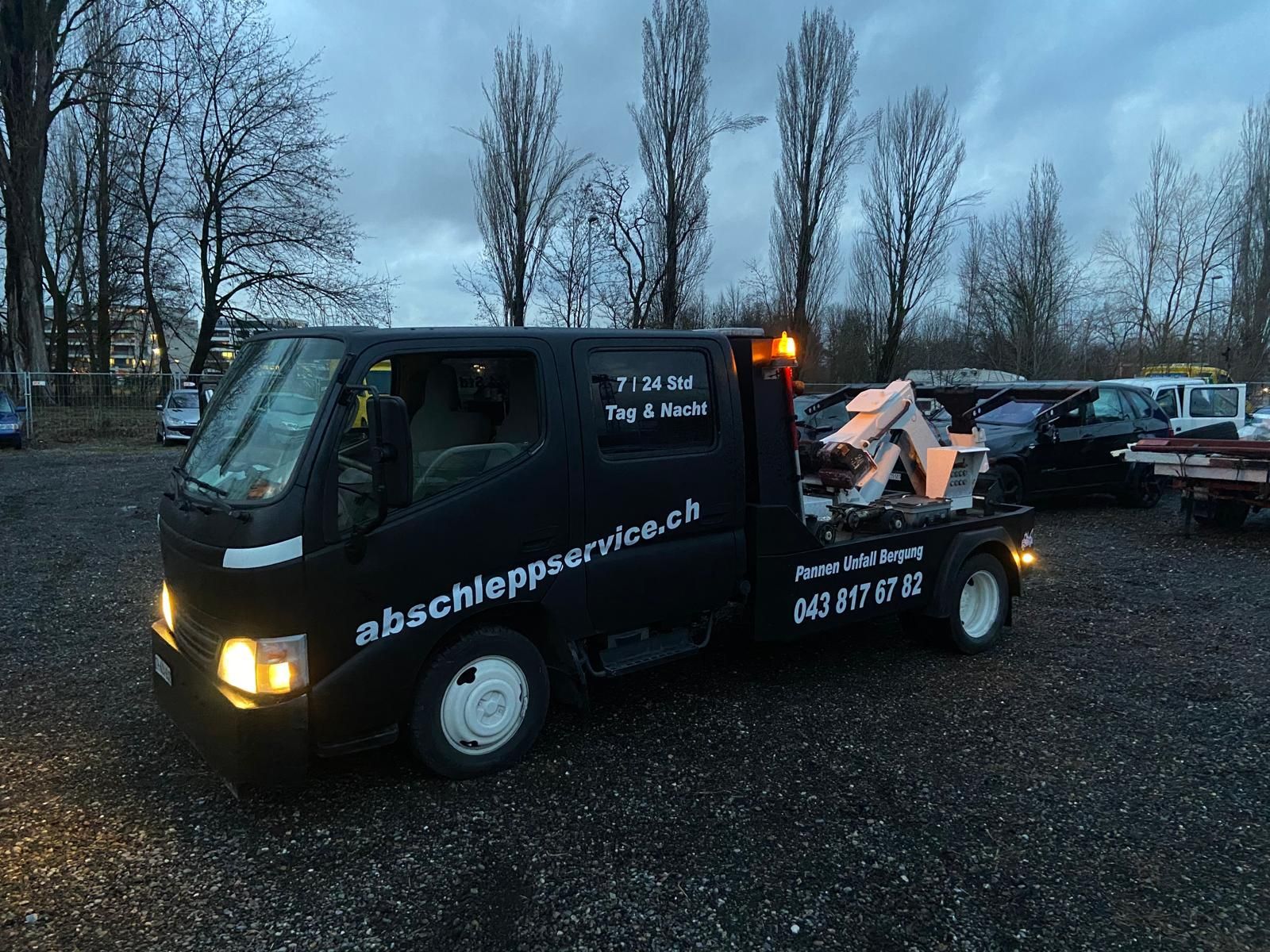 Ein Strassenarbeiter in einer Warnweste schüttelt einem Mann vor einem Abschleppwagen die Hand.