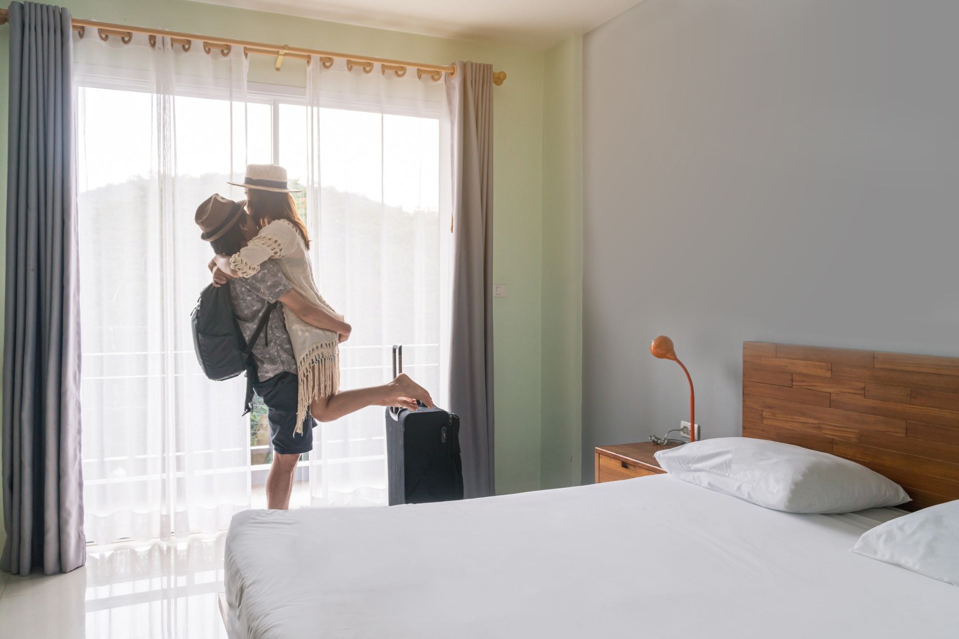 Un hombre lleva a una mujer en sus brazos en una habitación de hotel.
