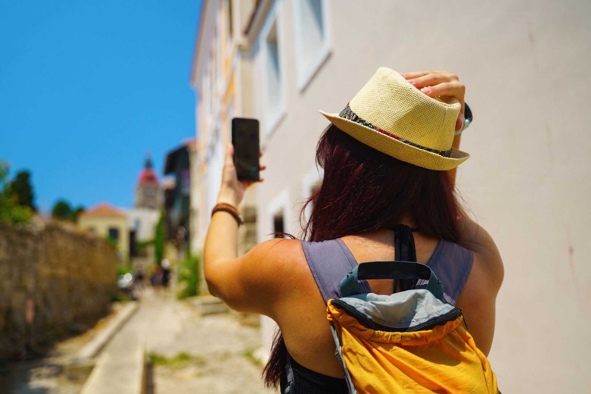 Una mujer con sombrero y mochila se toma una foto con su teléfono.