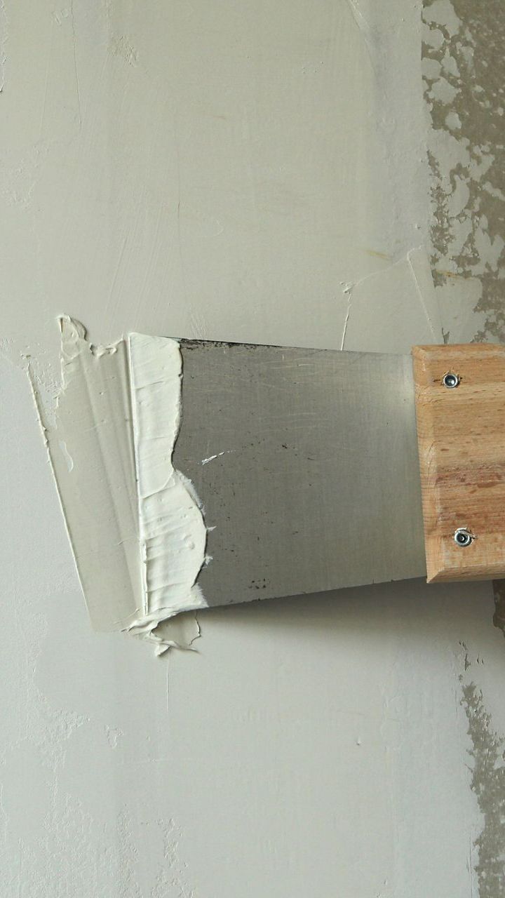 Personne en train d'étaler de l'enduit avec un couteau de plaquiste 