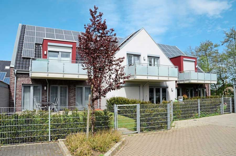 Ein Haus mit einem Zaun darum und einem Baum davor.