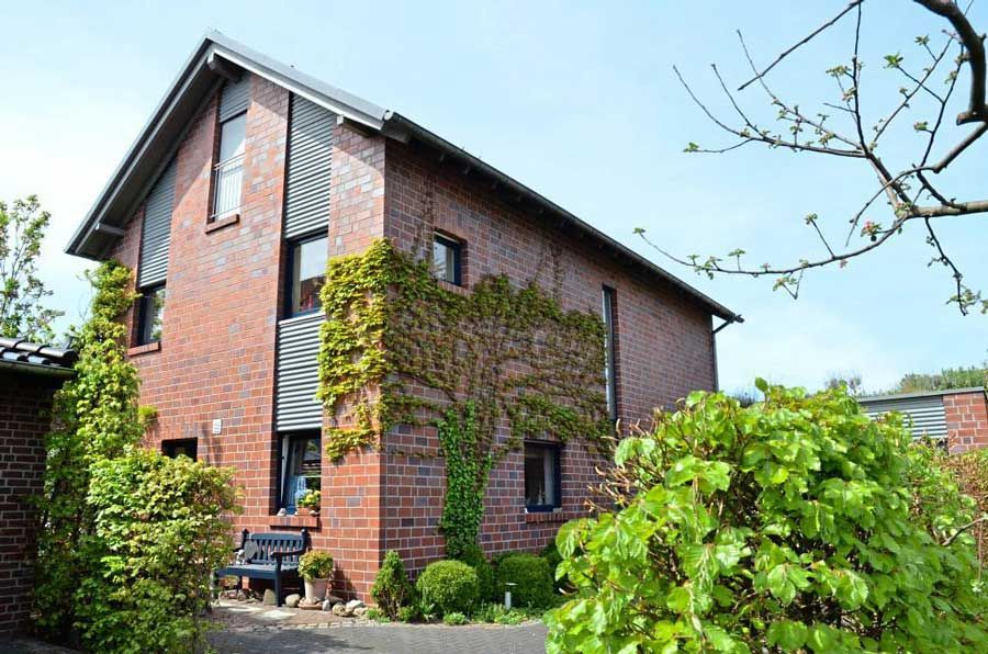 Ein Backsteinhaus mit einer blauen Bank davor.