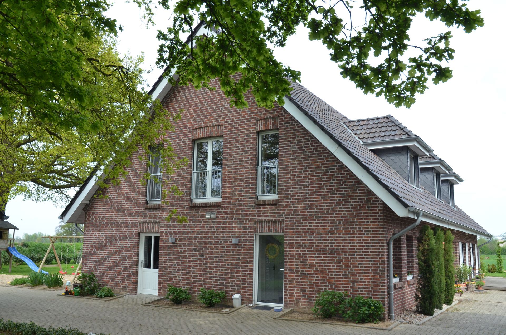 Ein großes rotes Backsteinhaus mit einem grauen Dach