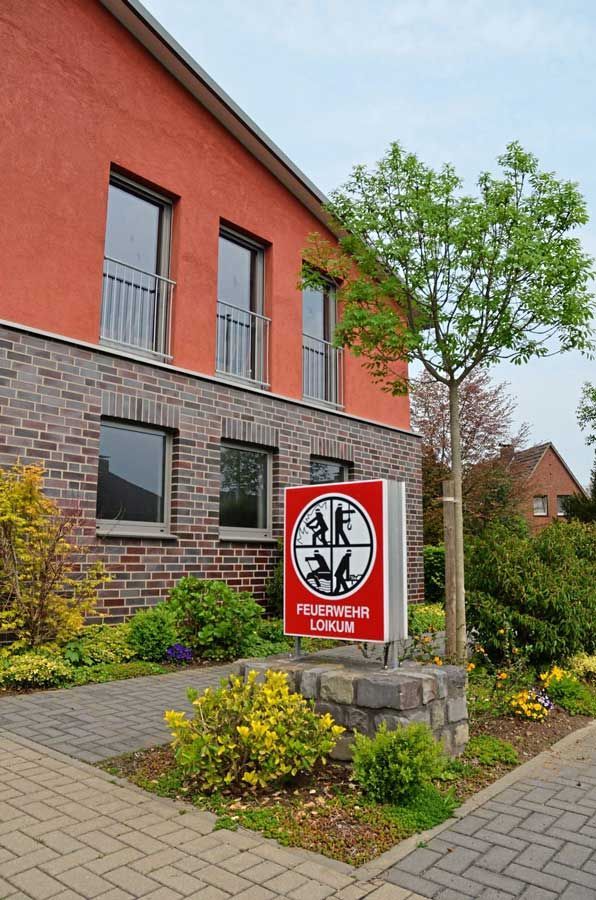 Ein rotes Backsteingebäude mit einem Schild davor.