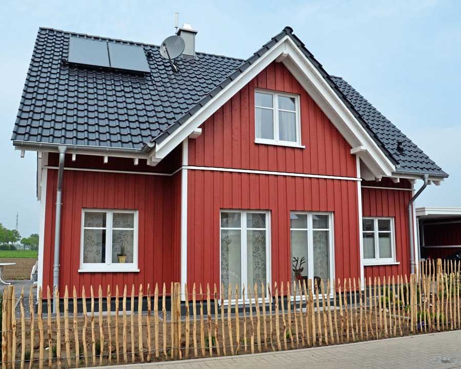 Ein rotes Haus im schwedischen Stil mit einem Holzzaun davor