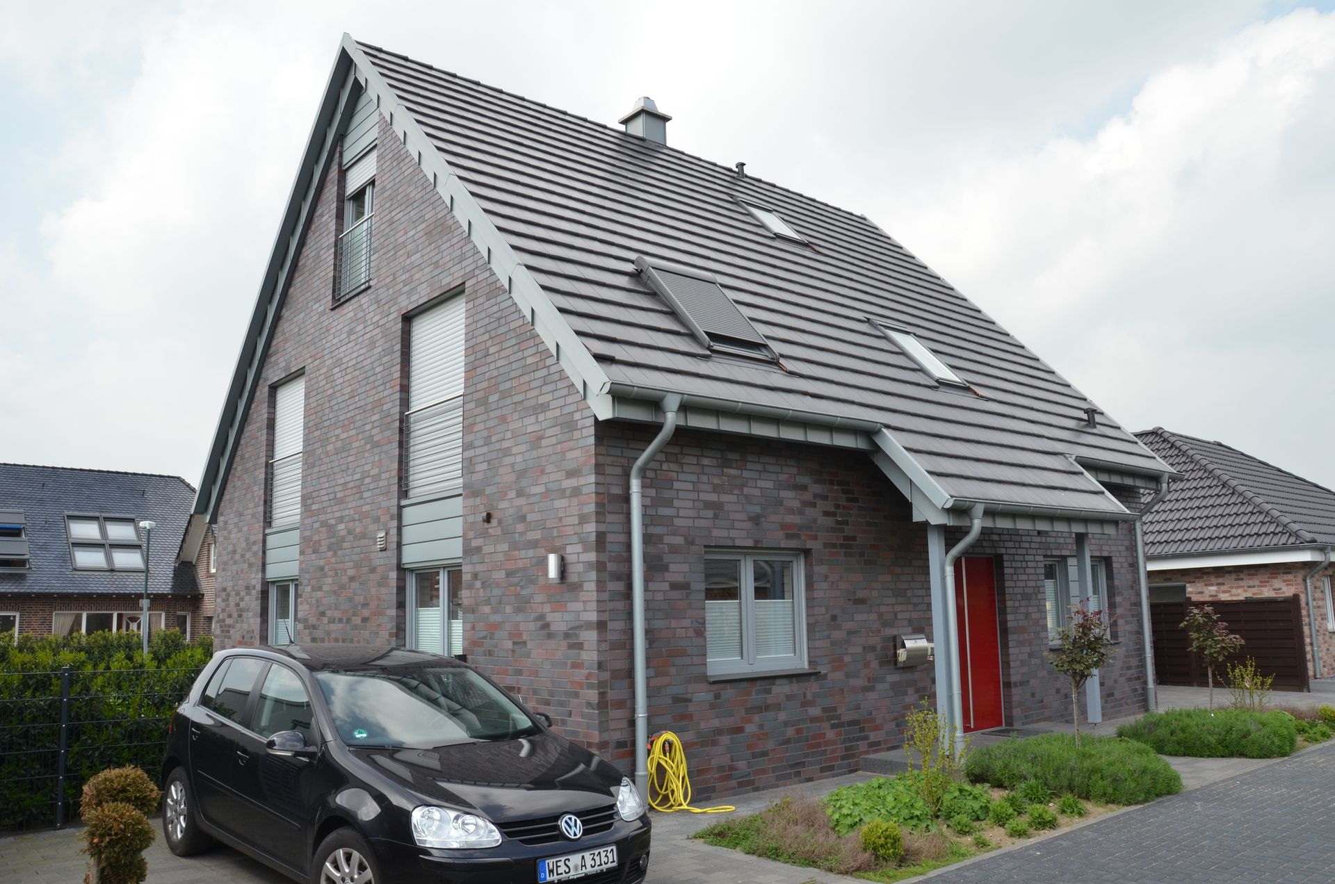 Ein schwarzes Auto steht vor einem Backsteinhaus