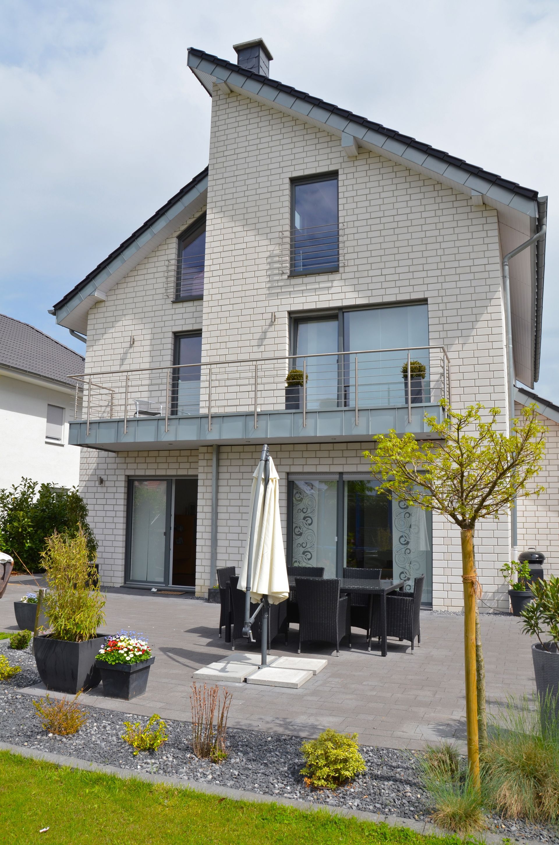 Ein großes weißes Backsteinhaus mit einer Terrasse und einem Sonnenschirm davor.