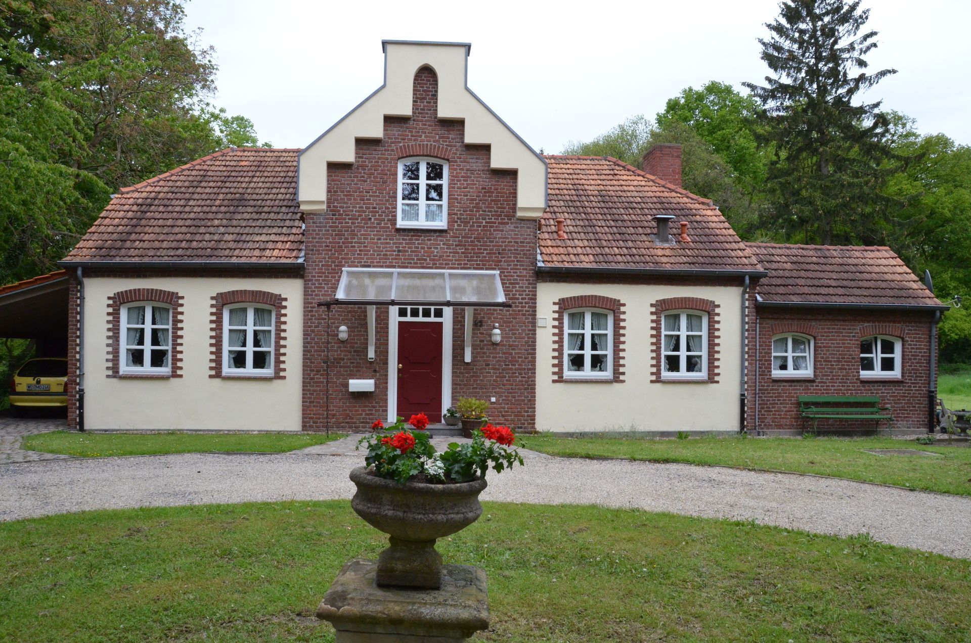 Ein großes Backsteinhaus mit einer roten Tür und weißen Verzierungen