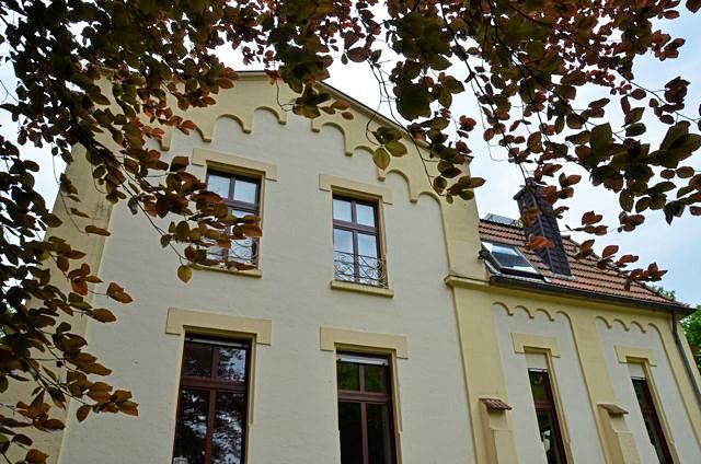 Ein großes Gebäude mit vielen Fenstern ist von Bäumen umgeben.