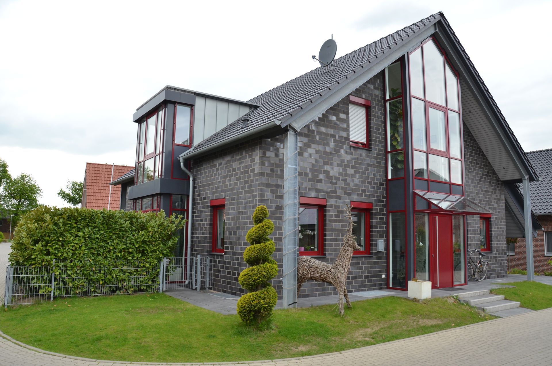 Ein großes Backsteinhaus mit einer roten Tür und vielen Fenstern