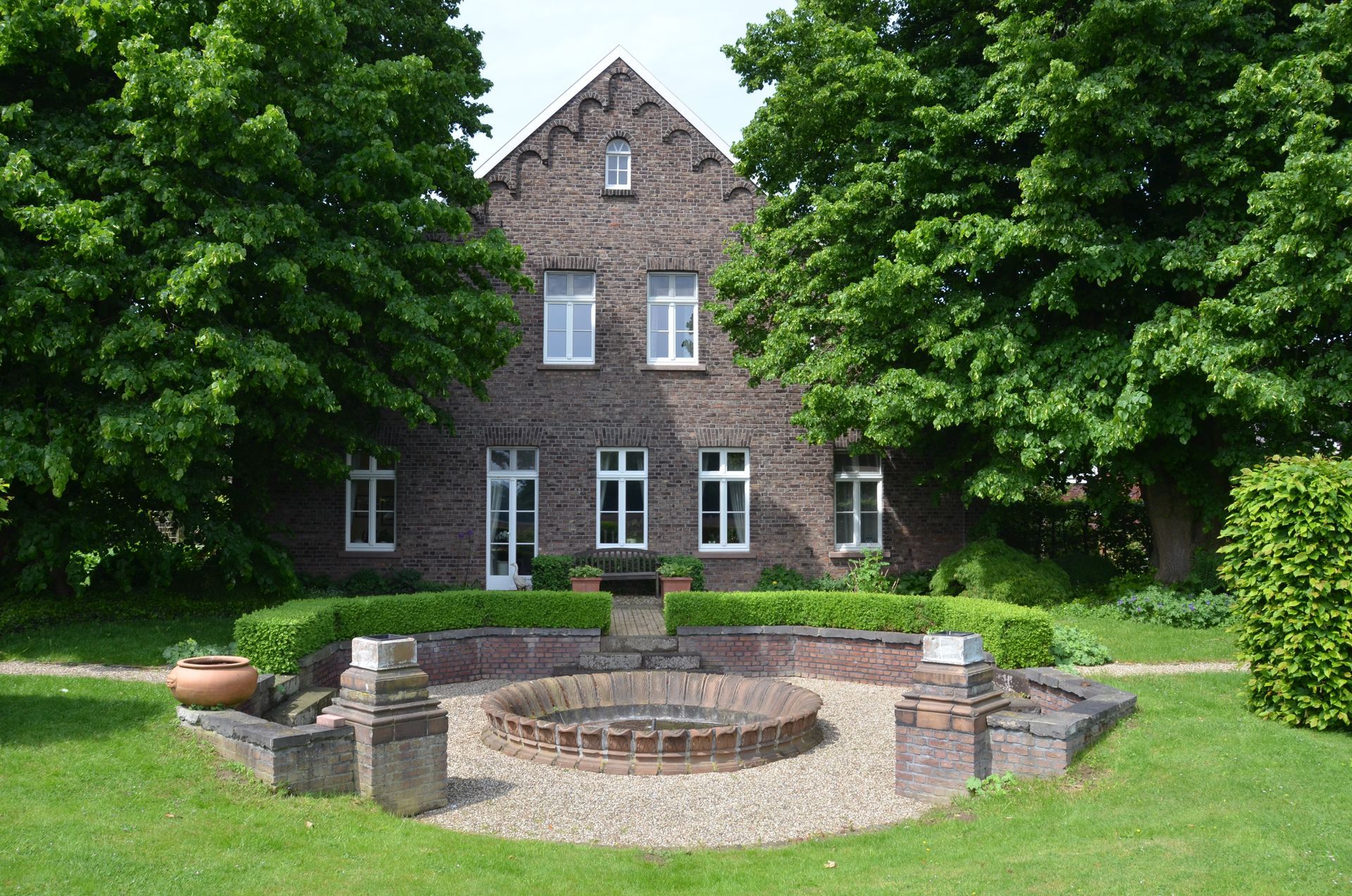 Ein großes Backsteinhaus mit einem Brunnen davor