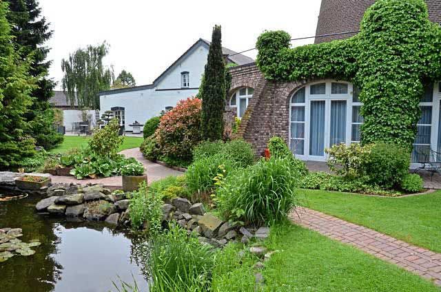 Ein Haus mit einem Teich davor und einem Weg, der dorthin führt.