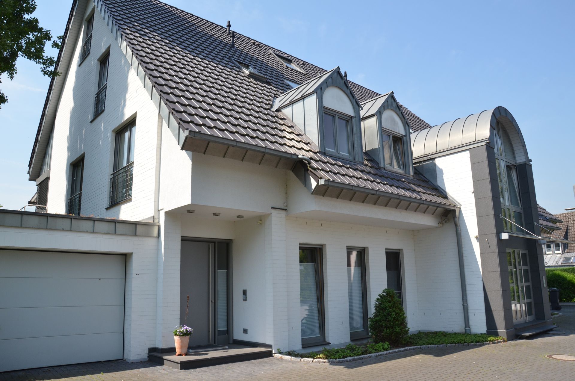 Ein weißes Haus mit grauem Dach und einer Garage