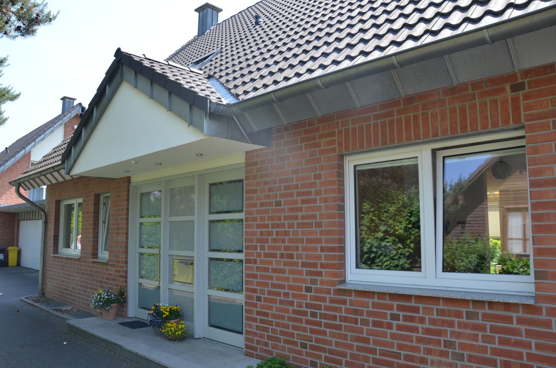 Ein rotes Backsteinhaus mit einer weißen Tür und Fenstern