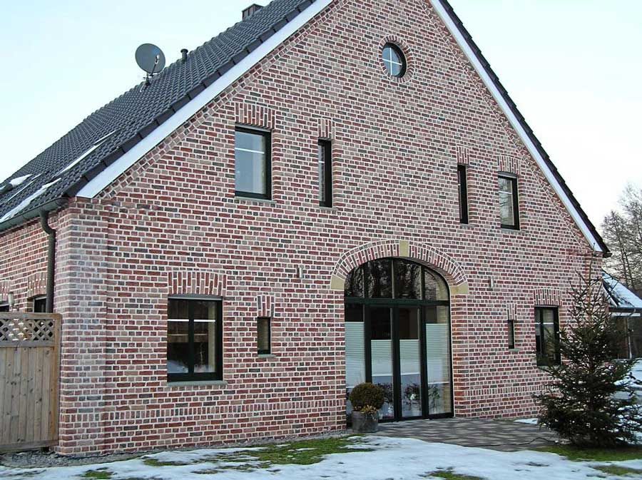 Ein großes modernes Backsteinhaus mit einem schwarzen Dach.