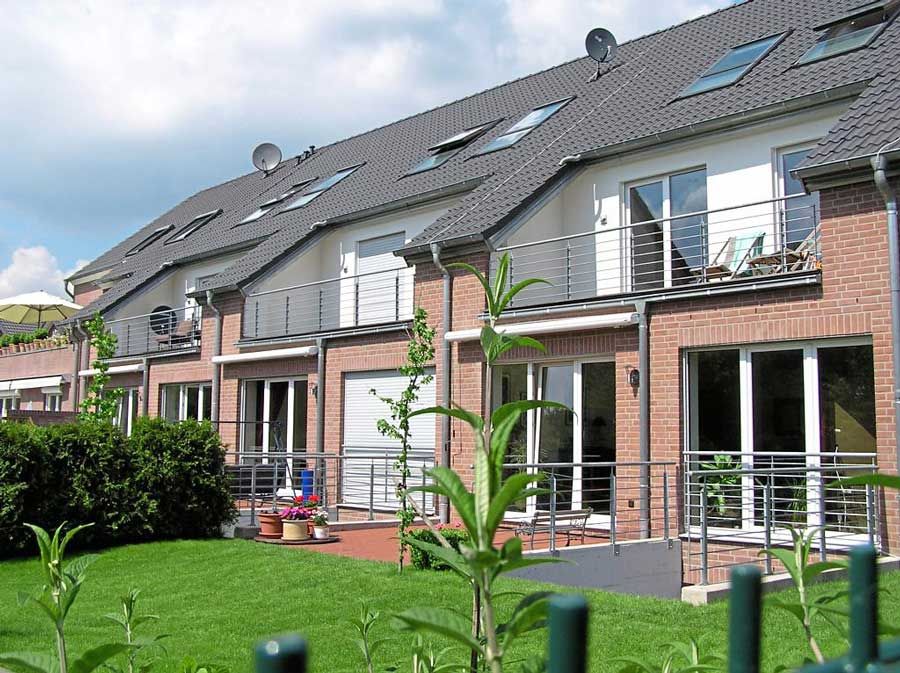 Eine Häuserzeile mit Balkonen und einem grünen Zaun