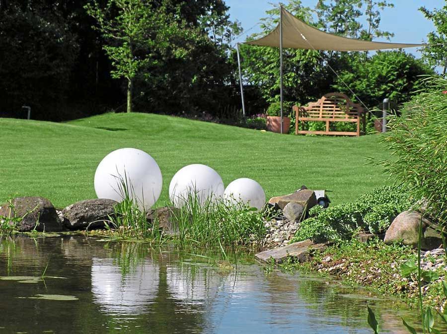 Ein Teich in einem Garten mit einer Bank im Hintergrund