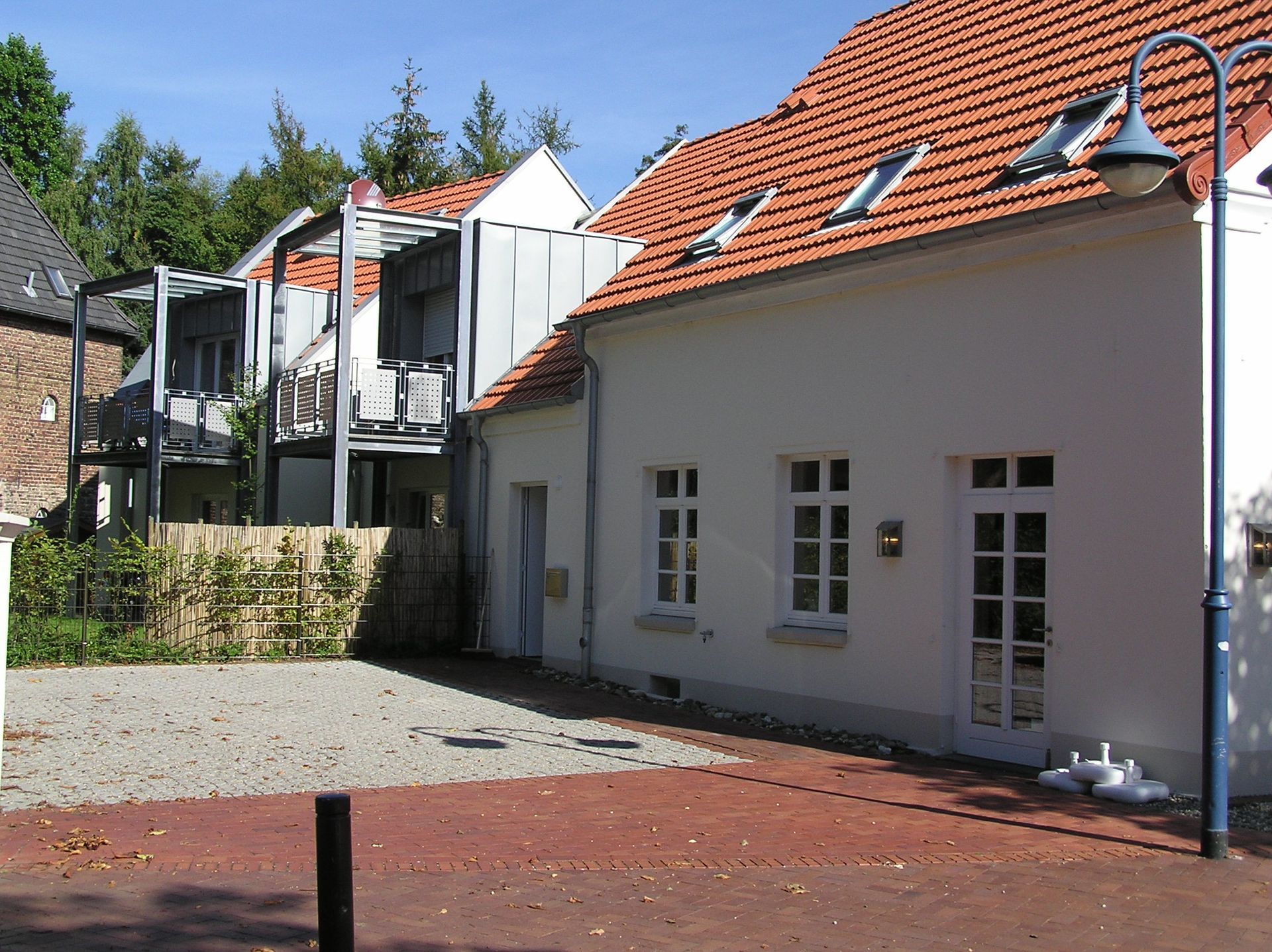 Ein weißes Gebäude mit einem roten Ziegeldach und einer Straßenlaterne davor