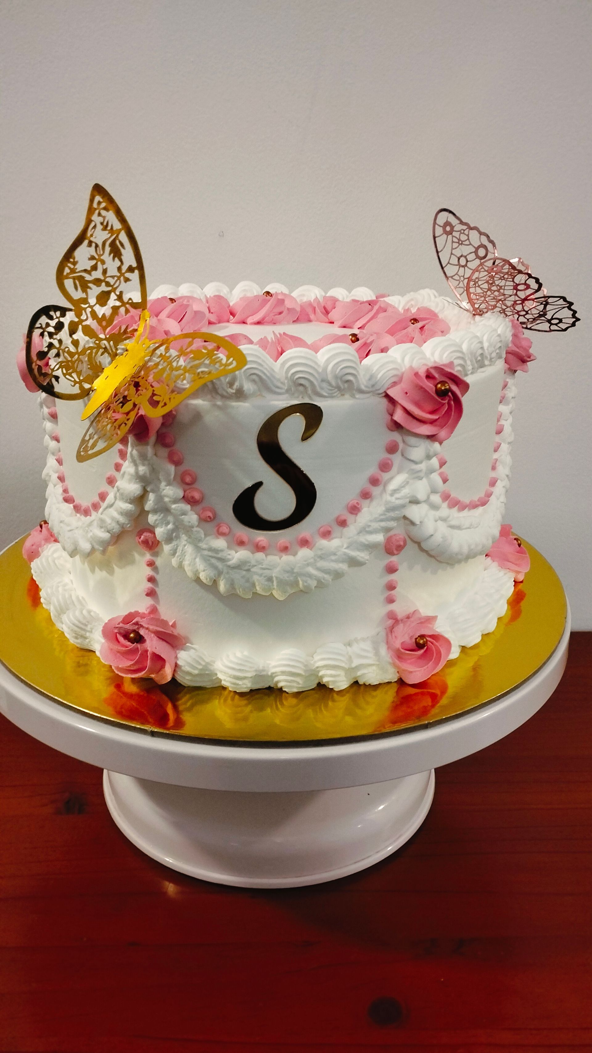 Un pastel con la letra s está sobre un soporte para pasteles.