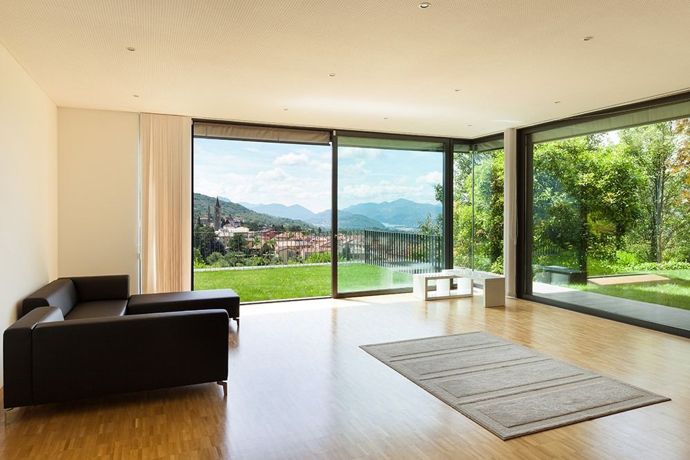 Ein Wohnzimmer mit Sofa, Teppich und großen Fenstern.