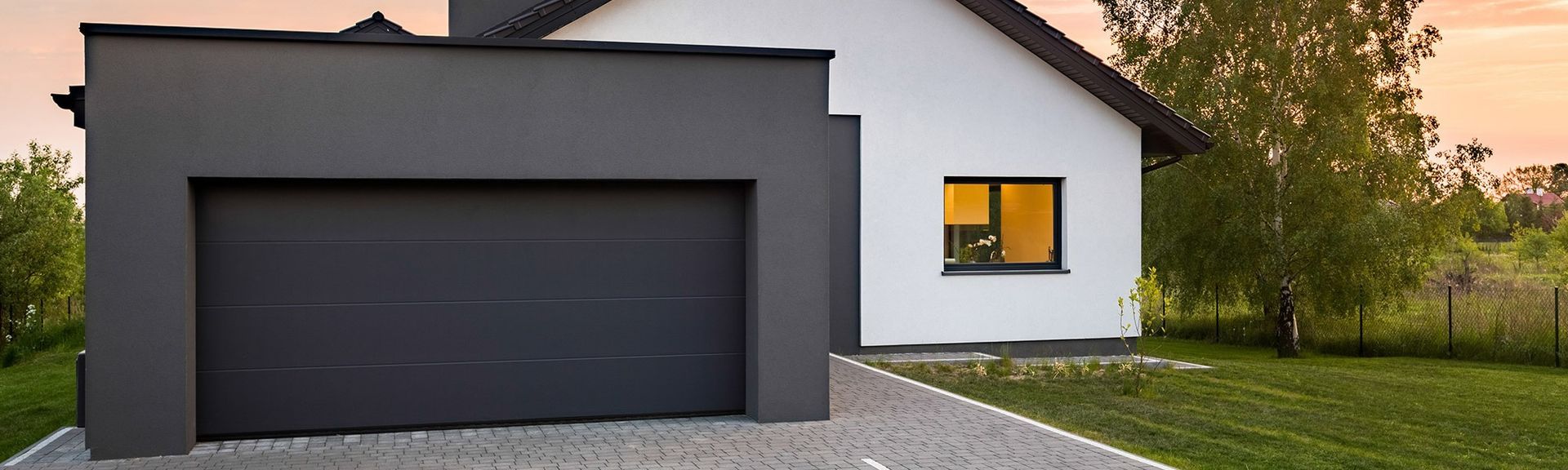Ein weißes Haus mit einem schwarzen Garagentor davor.