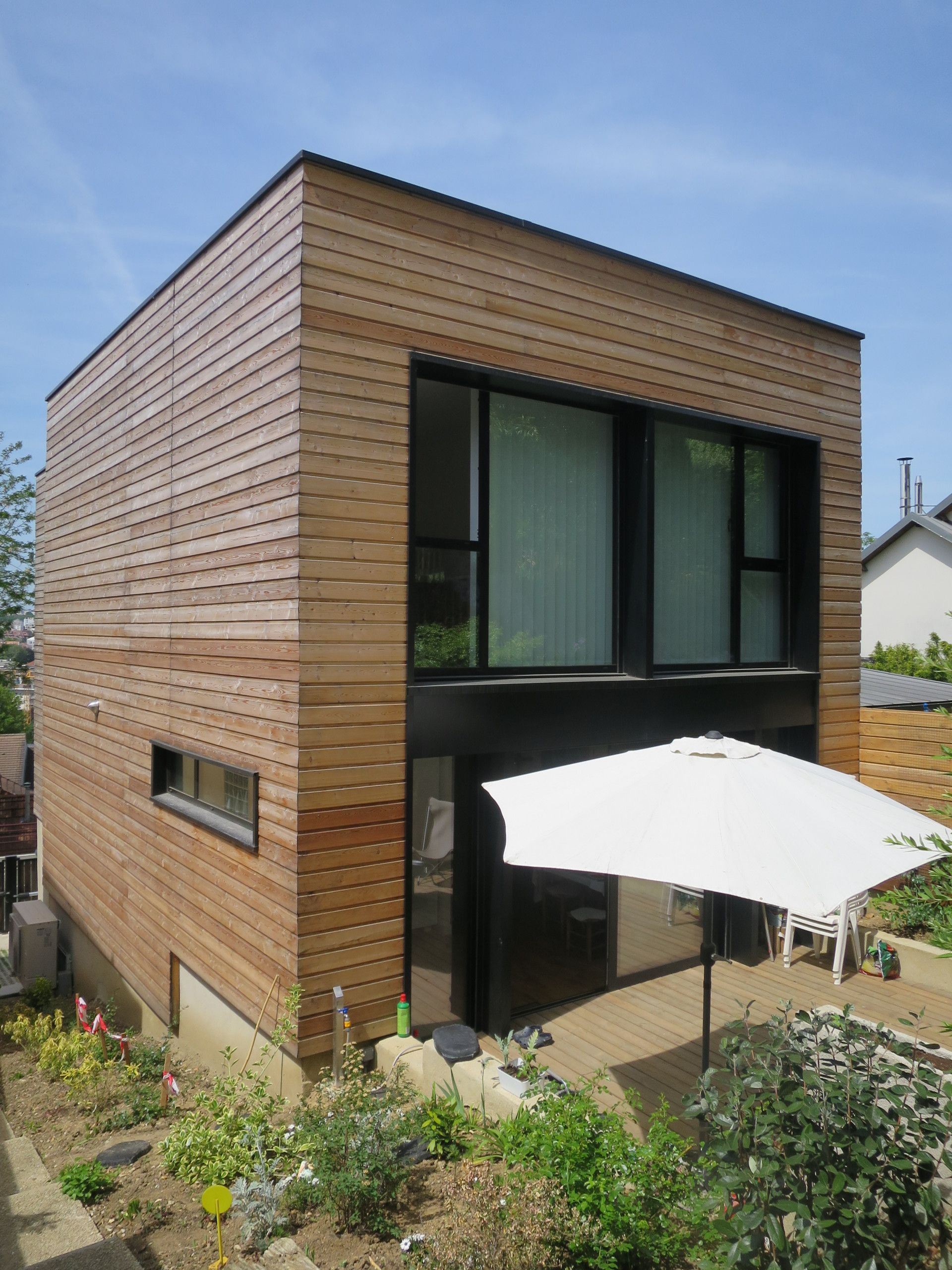 Maison en bois et aluminium avec un parasol