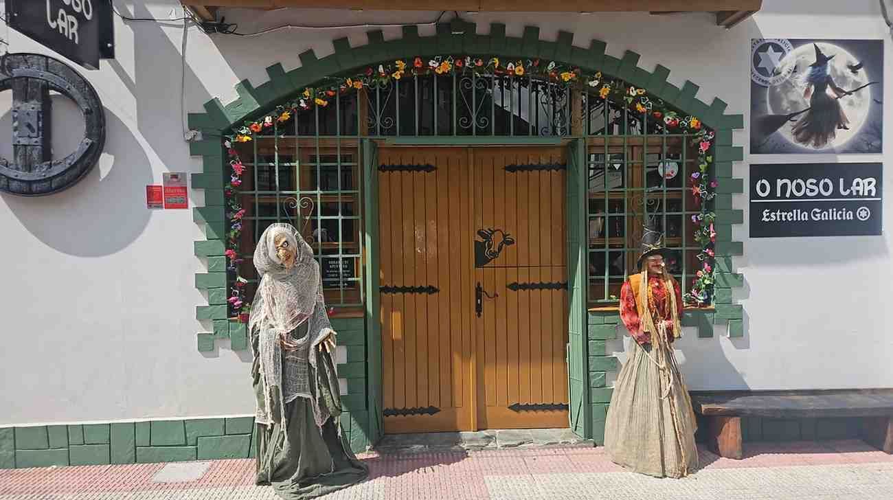 Fachada de tienda con puerta de madera, dos figuras disfrazadas y arco decorativo.