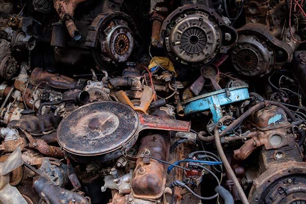 Un montón de piezas de coche oxidadas, incluidos motores y embragues.