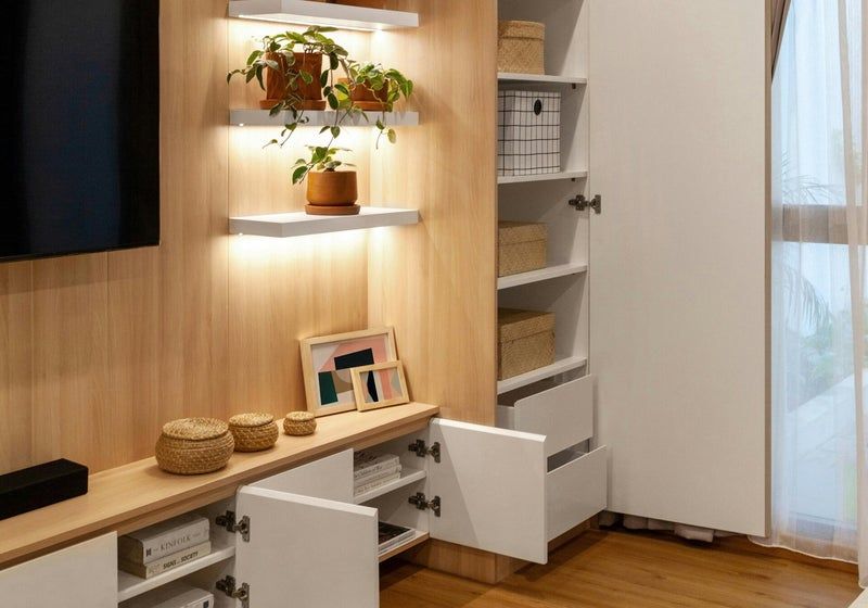 Un meuble TV en bois clair avec des placards blancs, des étagères ouvertes et des plantes